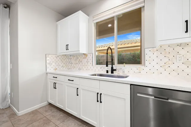 a view of an empty room and kitchen view with wooden floor