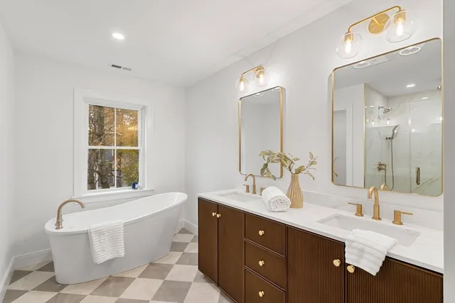 a bathroom with a double vanity sink bathtub mirror and toilet