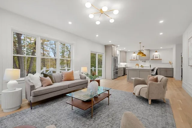 a living room with furniture and a large window with kitchen view