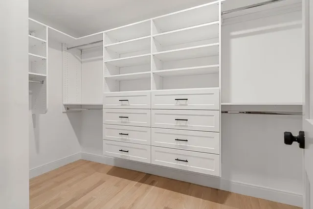 a view of an empty room with wooden floor and windows