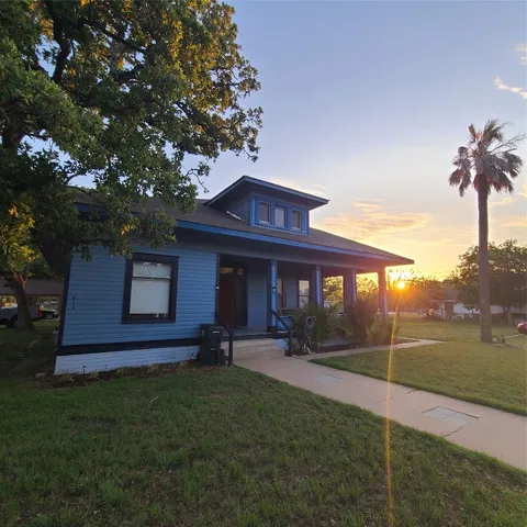 a view of a yard in front of a house with a large tree