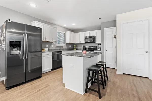 a kitchen with a refrigerator a stove and a microwave oven with wooden floor