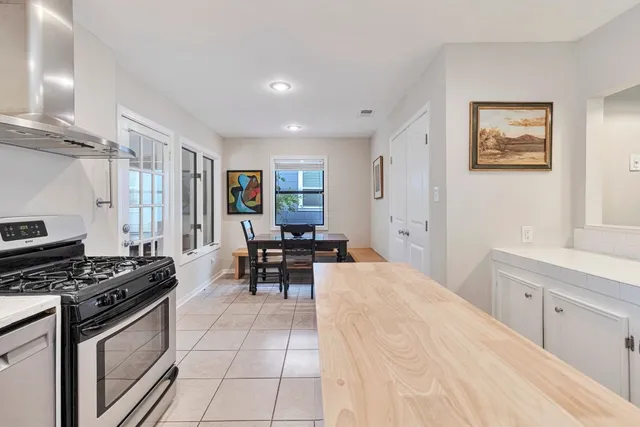a kitchen with stainless steel appliances a stove a sink white cabinets and a dining table
