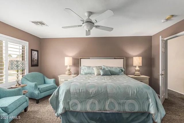 a bedroom with a bed couches and windows