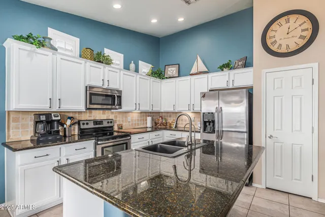 a kitchen with stainless steel appliances granite countertop a refrigerator a stove and a sink with wooden floor