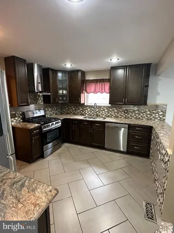 a kitchen with stainless steel appliances granite countertop a stove a sink dishwasher and a refrigerator