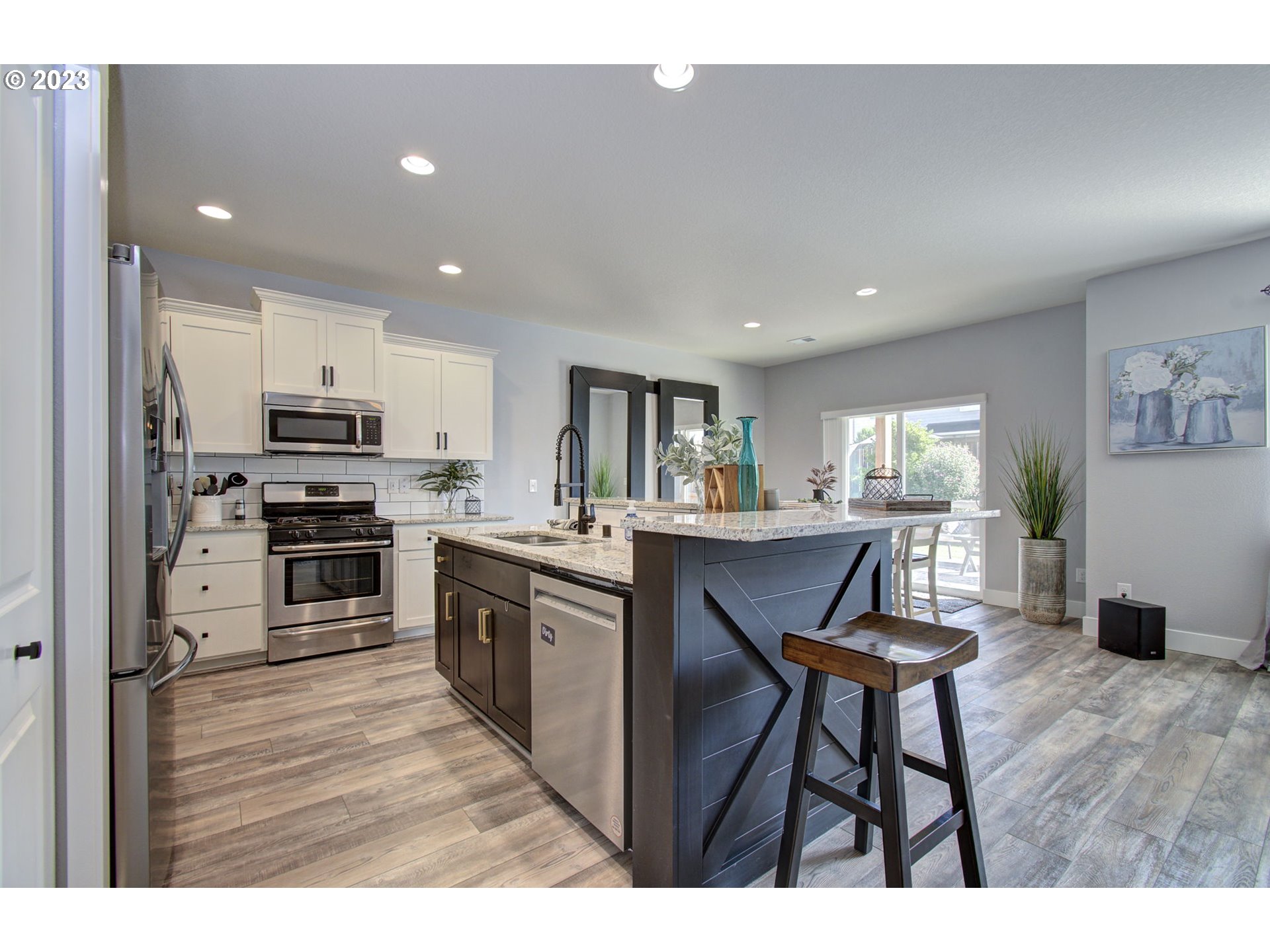 871 North 35th Avenue Ridgefield, WA 98642 - Photo 7 of 36 a kitchen with stainless steel appliances granite countertop a stove top oven a sink dishwasher a dining table and chairs with wooden floor