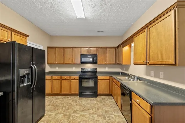 a kitchen with stainless steel appliances granite countertop a refrigerator a sink dishwasher a stove with wooden cabinets and floor