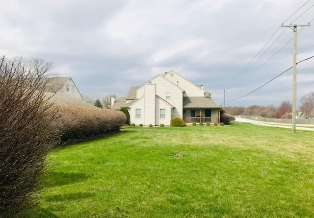 a view of a house with a big yard and large trees