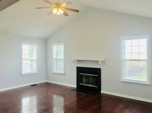 an empty room with wooden floor fireplace and windows