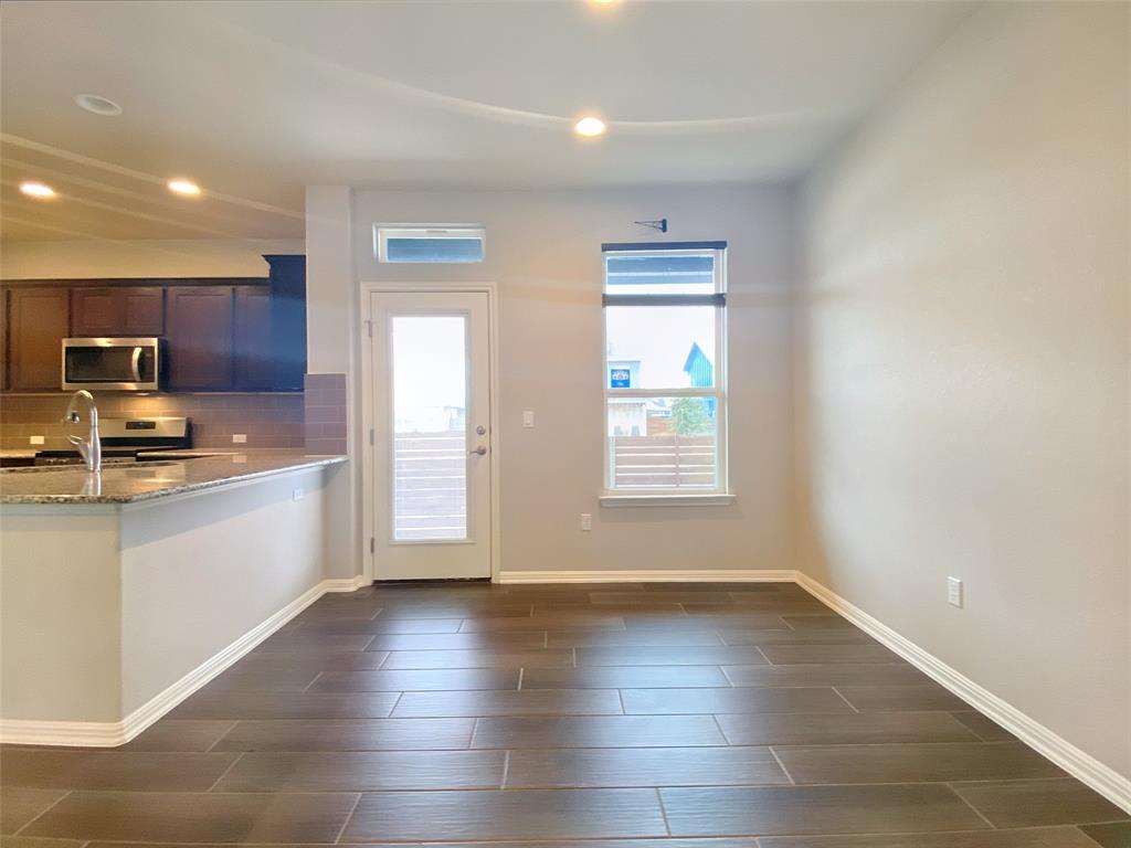 8901 Panhandle Drive Austin, TX 78747 - Photo 8 of 21 Open-concept kitchen and dining area featuring dark wood-finish tile flooring, recessed lighting, and a kitchen island with a granite countertop