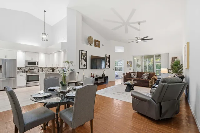 a living room with furniture kitchen view and a wooden floor