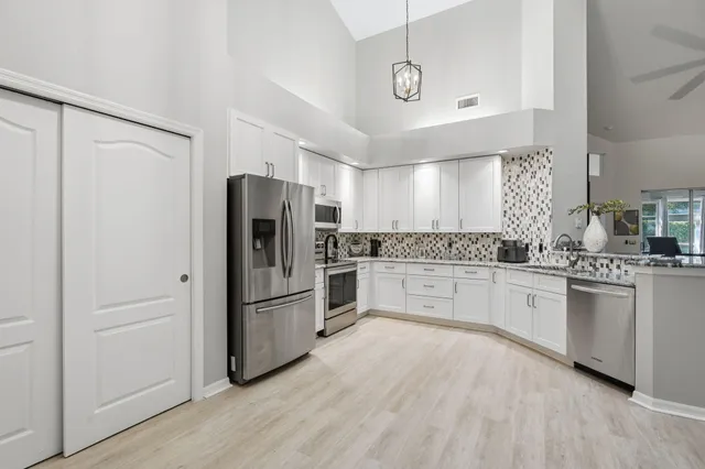 a kitchen with granite countertop stainless steel appliances a refrigerator and cabinets