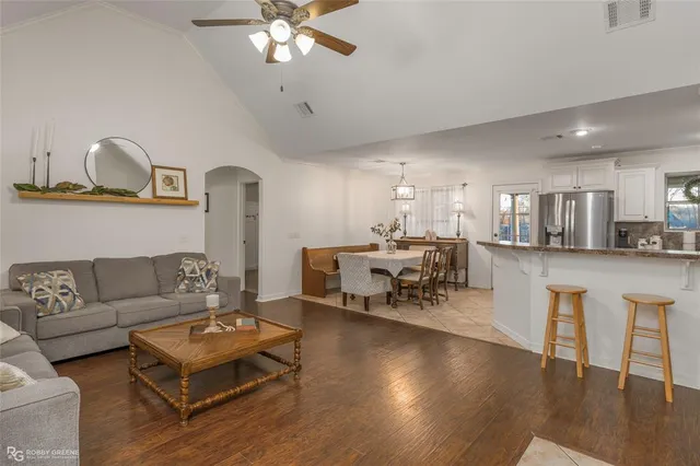 a living room with furniture and a dining table with wooden floor