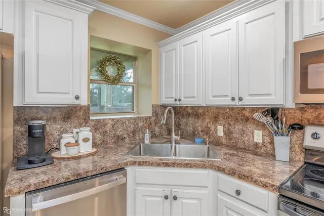 a kitchen with granite countertop stainless steel appliances white cabinets granite counter tops and a wooden floor