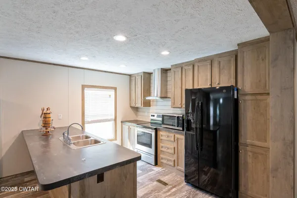 a kitchen with stainless steel appliances granite countertop a refrigerator and a stove top oven