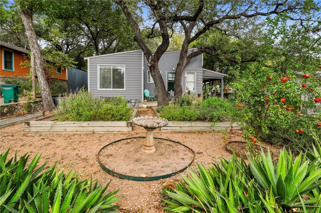 a view of a house with a small yard plants and large trees