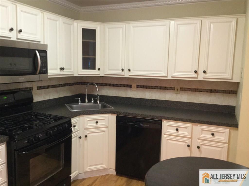 2803 Ridgefield Court Helmetta, NJ 08828 - Photo 6 of 20 a kitchen with granite countertop white cabinets and black appliances
