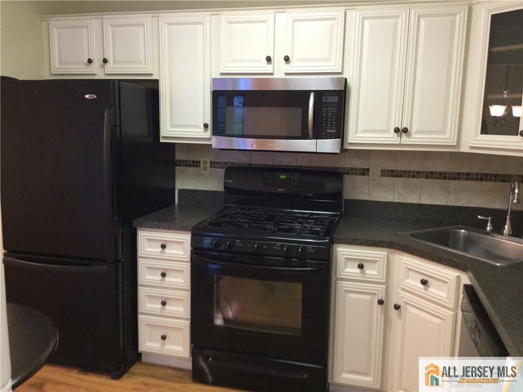 2803 Ridgefield Court Helmetta, NJ 08828 - Photo 7 of 20 a kitchen with granite countertop white cabinets and black appliances