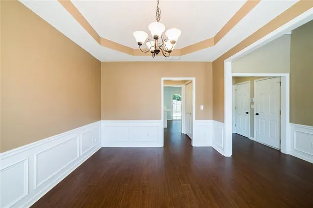 a view of an empty room with wooden floor and a chandelier