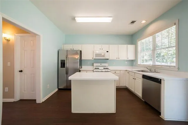 a kitchen with kitchen island white cabinets and white appliances
