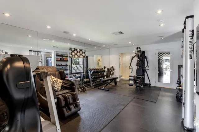 a kitchen with stainless steel appliances kitchen island granite countertop a refrigerator a sink dishwasher and white cabinets with wooden floor