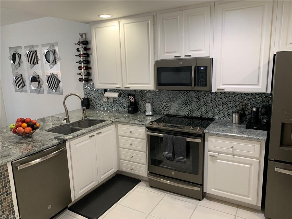 3518 Zanzibar Way Naples, FL 34119 - Photo 1 of 13 a kitchen with granite countertop white cabinets stainless steel appliances and sink