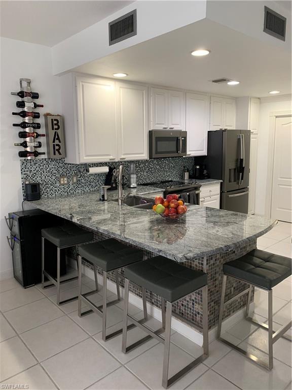 3518 Zanzibar Way Naples, FL 34119 - Photo 2 of 13 a kitchen with stainless steel appliances kitchen island granite countertop a sink and cabinets