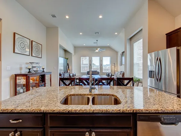 a kitchen with kitchen island granite countertop a sink a counter top space and stainless steel appliances