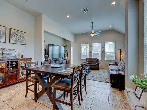 a dining hall view with a large dining table and chairs with kitchen view