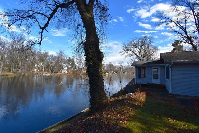 a view of a small house with a large tree and a yard