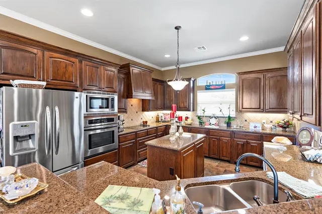 a kitchen with stainless steel appliances kitchen island granite countertop a sink stove and refrigerator