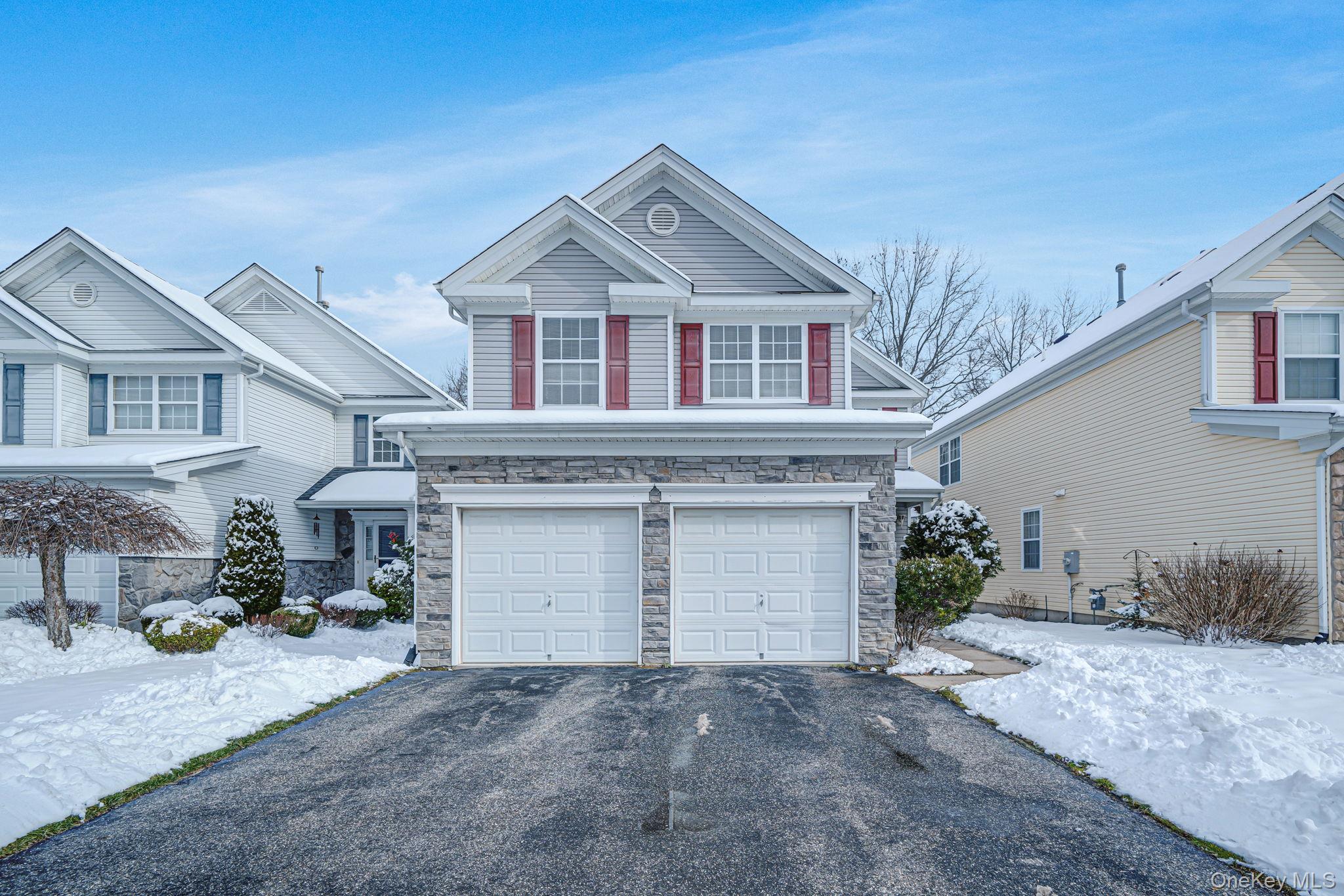View of front of home with stone siding, driveway, and a garage