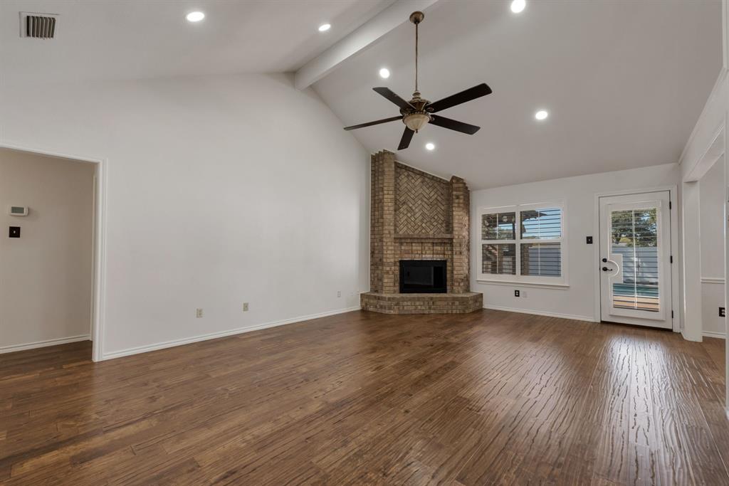 3305 Timber View Circle Bedford, TX 76021 - Photo 15 of 26 an empty room with wooden floor a ceiling fan a fireplace and windows