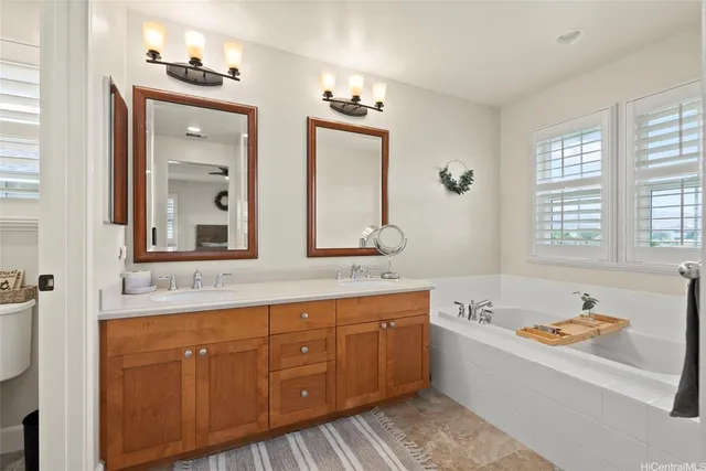 a bathroom with a tub double vanity sink and mirror
