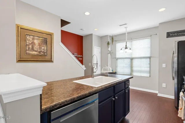 a kitchen with kitchen island granite countertop a sink refrigerator and microwave