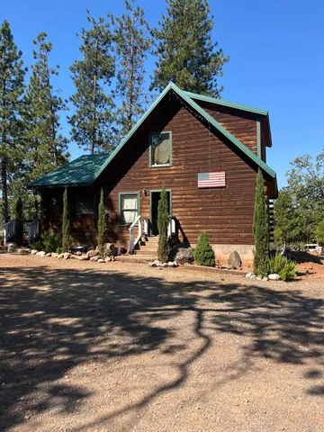 a view of the house with backyard and trees in the background