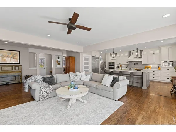 a living room with furniture kitchen view and a wooden floor