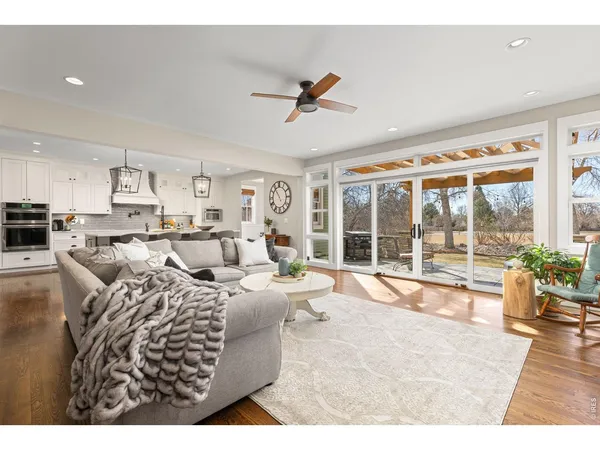 a living room with furniture large windows and kitchen view
