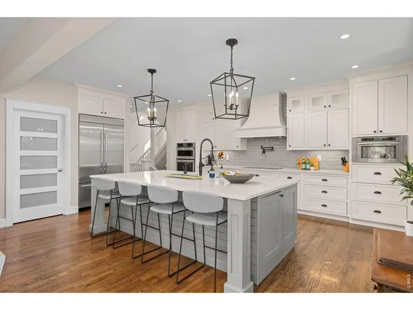 a kitchen with kitchen island granite countertop a sink cabinets and wooden floor