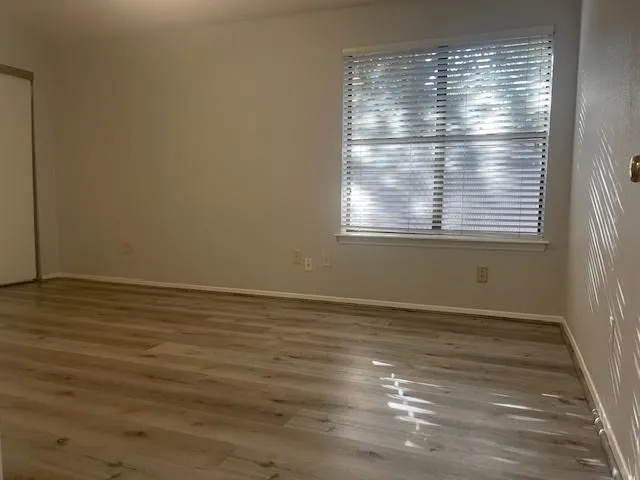 a view of an empty room with wooden floor and a window