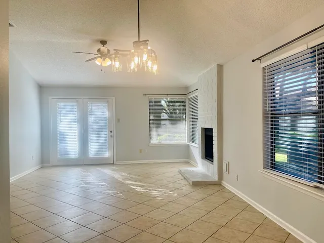 a view of an empty room with window and chandelier fan