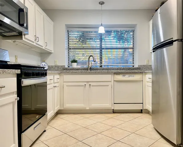 a kitchen with granite countertop white cabinets and white appliances