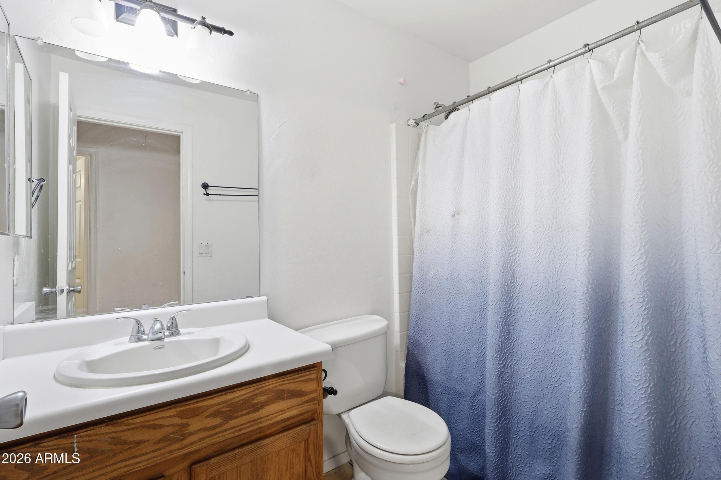 11964 West Granada Road Avondale, AZ 85392 - Photo 26 of 36 a bathroom with a granite countertop sink toilet and a mirror