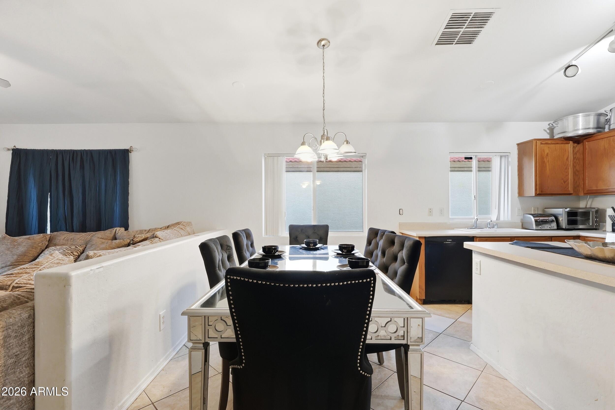 11964 West Granada Road Avondale, AZ 85392 - Photo 10 of 36 a kitchen with granite countertop a sink a stove a dining table and chairs