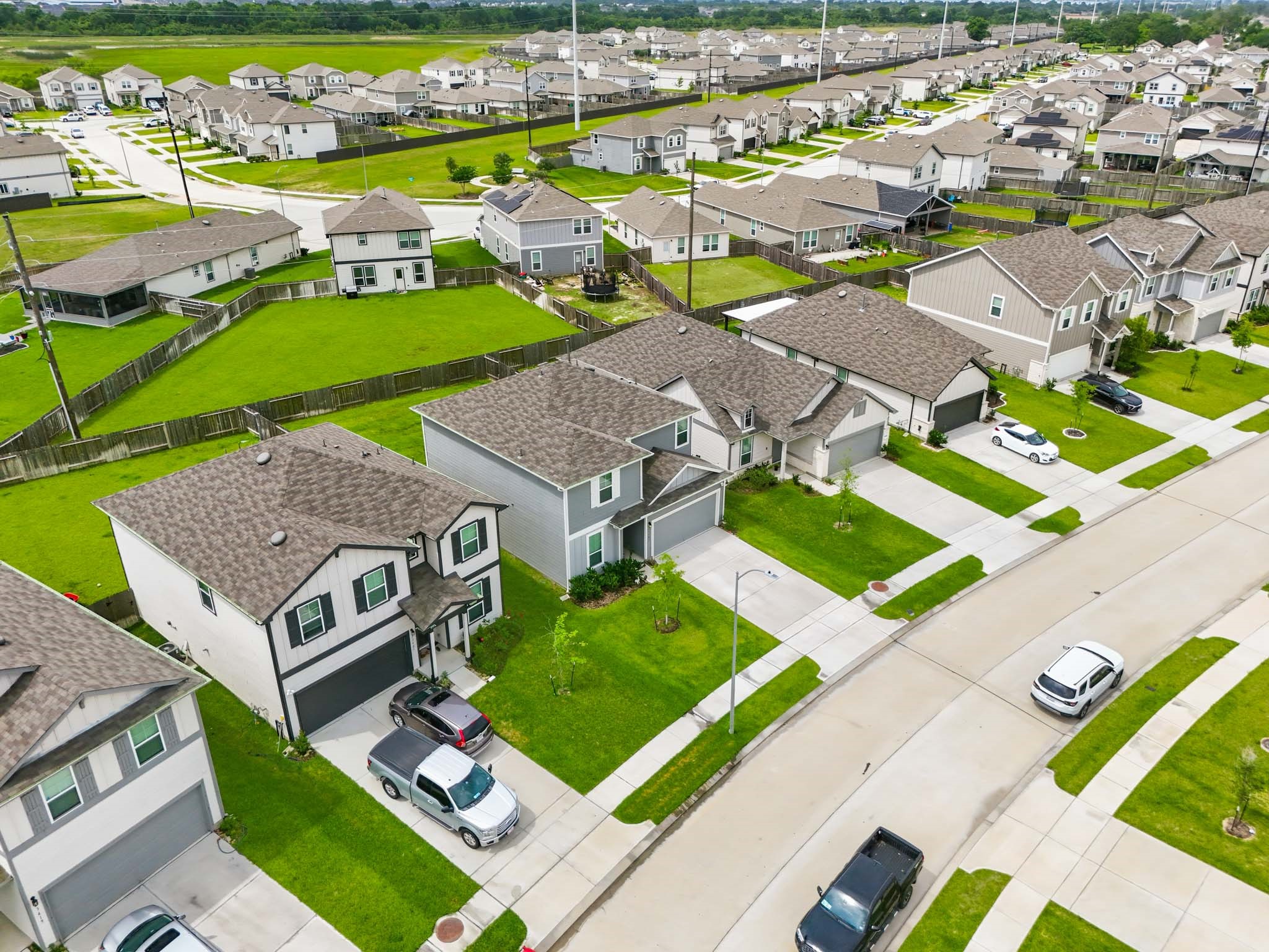 23427 Weir Box Road Hockley, TX 77447 - Photo 27 of 32 An elevated, angled perspective highlighting the property’s position within the vibrant Windrow community. This view showcases the wide concrete driveway, sidewalks, and the cohesive architectural style of the surrounding neighborhood.