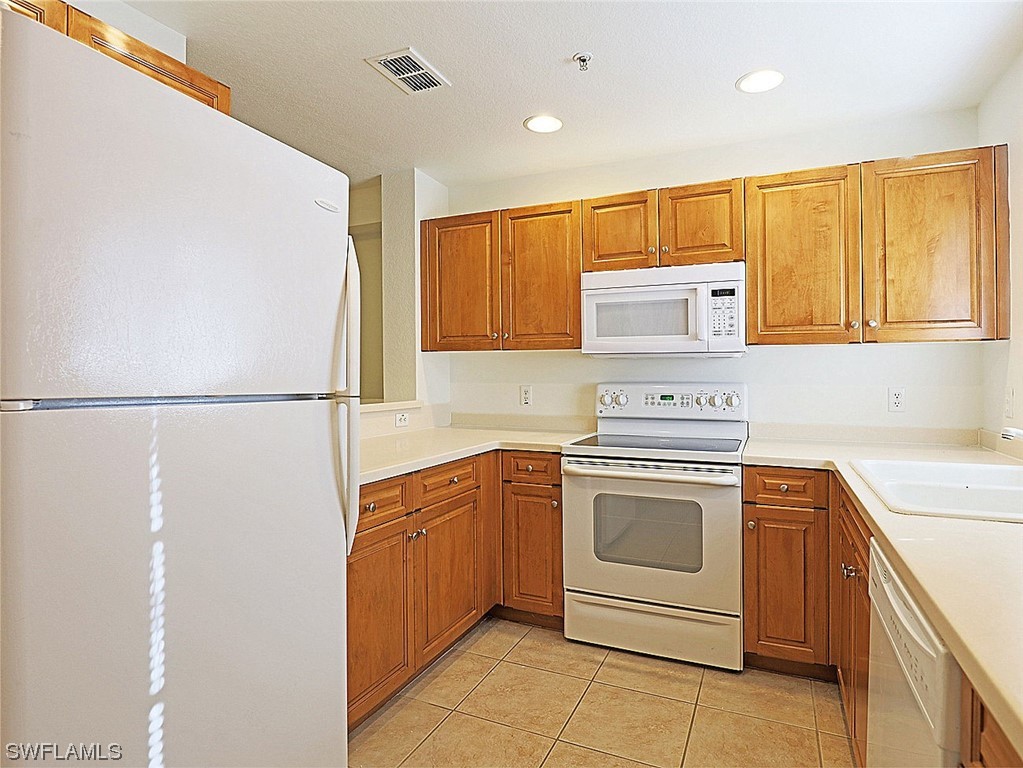 9419 Ivy Brook Run, Unit 1204 Fort Myers, FL 33913 - Photo 4 of 22 a kitchen with stainless steel appliances granite countertop a stove a sink and a refrigerator with cabinets