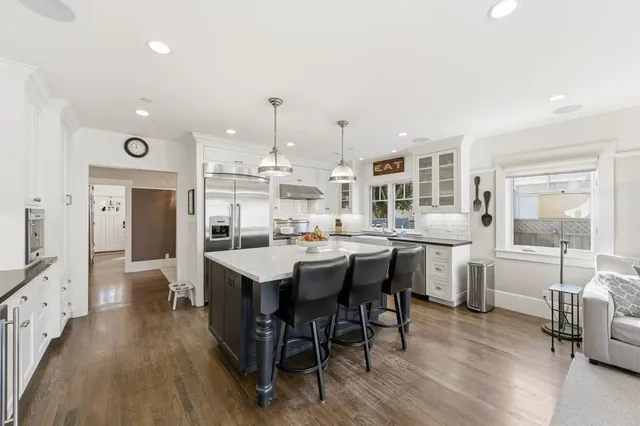 a dining hall with stainless steel appliances kitchen island a table and chairs in it