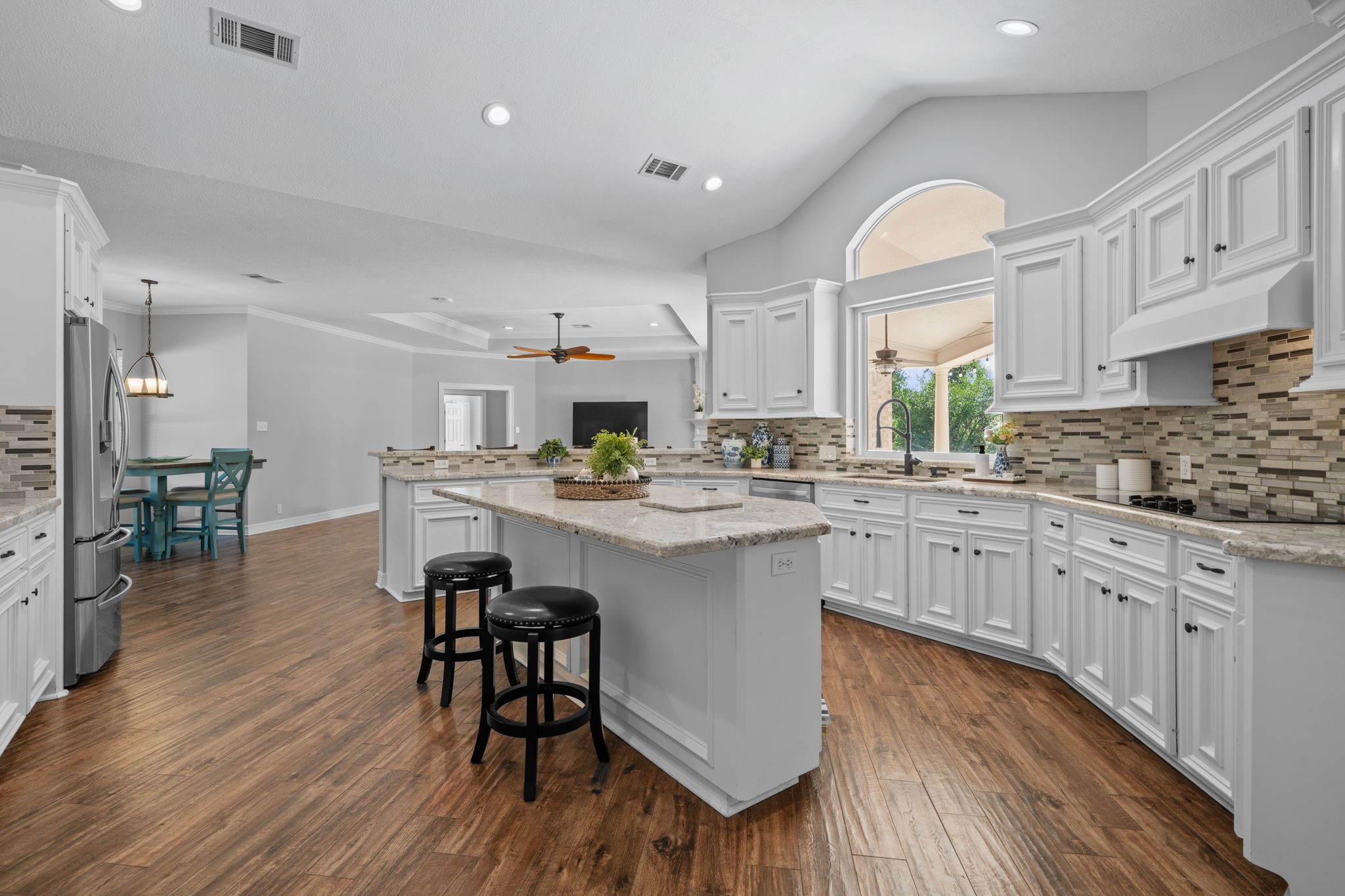 18355 Burkhardt Road Tomball, TX 77377 - Photo 4 of 50 a kitchen with stainless steel appliances kitchen island granite countertop a stove a sink dishwasher a microwave oven and a dining table with wooden floor