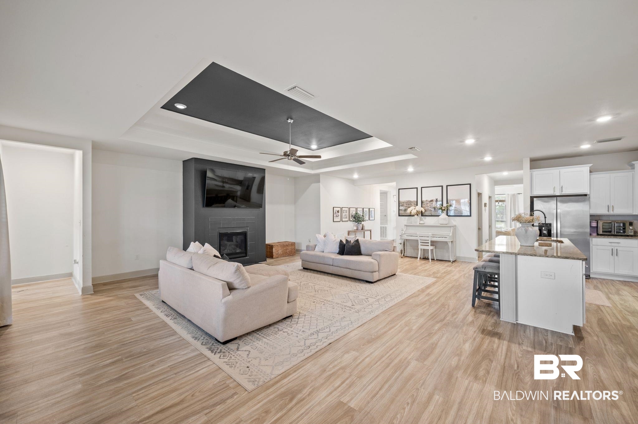 10169 Dunleith Loop Daphne, AL 36526 - Photo 22 of 40 Living area with a tray ceiling, a large fireplace, light wood finished floors, a ceiling fan, and recessed lighting
